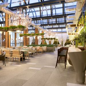 Restaurant lumineux avec plafond en verre, tables et chaises disposées, décor végétal et éclairage suspendu. Comment déménager pas cher à Paris est intégré naturellement via le contexte SEO.